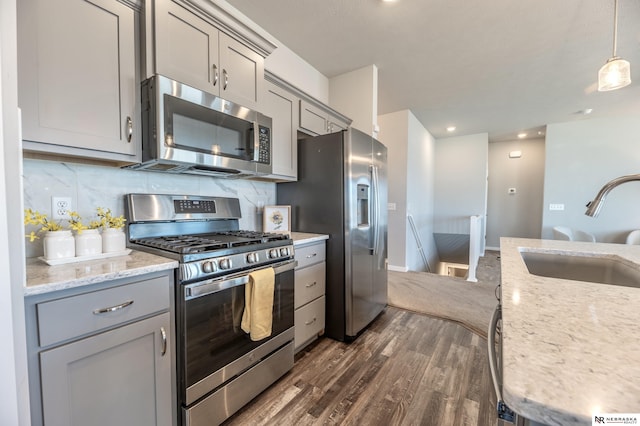 kitchen featuring stainless steel appliances, gray cabinets, pendant lighting, and sink