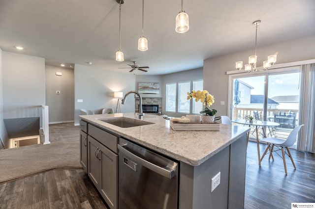 kitchen with stainless steel dishwasher, pendant lighting, a center island with sink, ceiling fan with notable chandelier, and sink