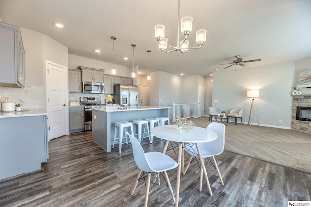 dining area featuring ceiling fan with notable chandelier, a fireplace, dark hardwood / wood-style flooring, and sink