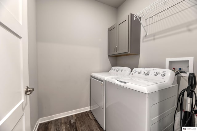 laundry room with washing machine and dryer, cabinets, and dark hardwood / wood-style floors