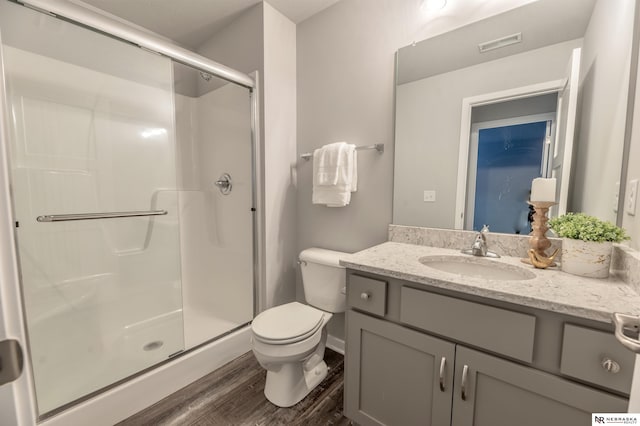 bathroom with hardwood / wood-style floors, an enclosed shower, vanity, and toilet