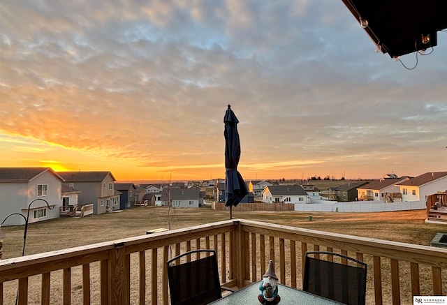 deck at dusk featuring a lawn