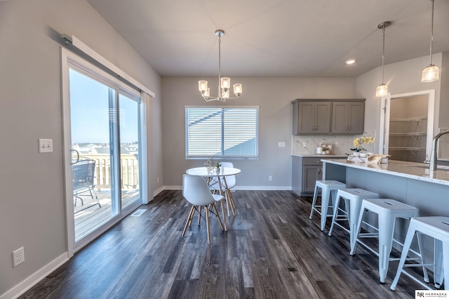 kitchen with a kitchen breakfast bar, gray cabinets, decorative backsplash, and hanging light fixtures