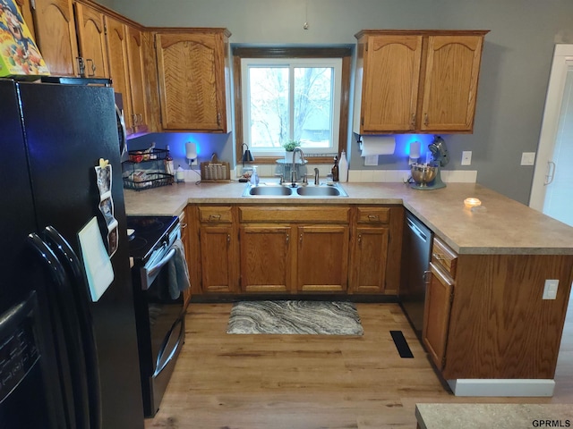 kitchen with kitchen peninsula, appliances with stainless steel finishes, light wood-type flooring, and sink