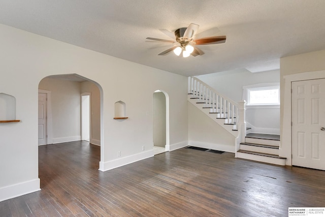 empty room with ceiling fan, a textured ceiling, and dark wood-type flooring