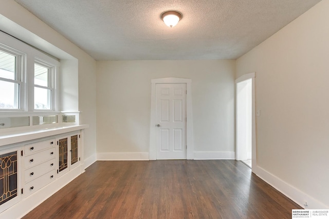 unfurnished room with dark hardwood / wood-style flooring and a textured ceiling