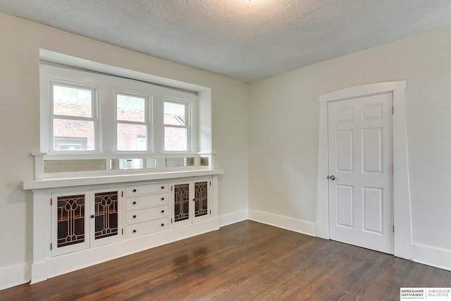 empty room featuring dark wood-type flooring and a textured ceiling