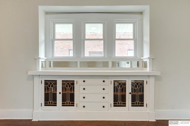 bar with dark hardwood / wood-style floors and white cabinetry