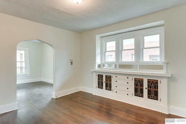 empty room with a textured ceiling and dark wood-type flooring