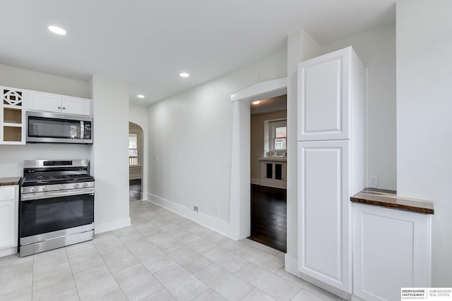 kitchen with light tile patterned flooring, white cabinets, and stainless steel appliances