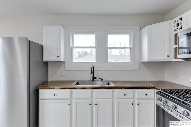 kitchen featuring butcher block countertops, white cabinets, sink, and stainless steel appliances