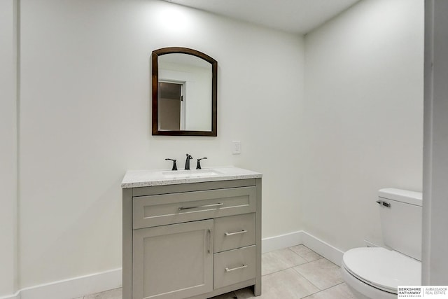 bathroom with toilet, vanity, and tile patterned floors