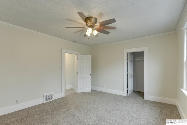 unfurnished bedroom with light carpet, crown molding, ceiling fan, a textured ceiling, and a closet