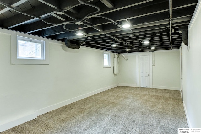 basement featuring light colored carpet and electric panel