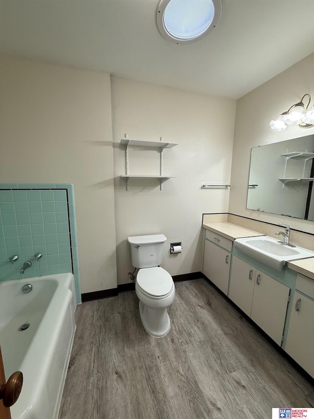 bathroom featuring a washtub, vanity, hardwood / wood-style flooring, and toilet