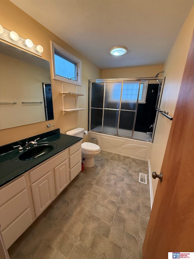 full bathroom featuring vanity, bath / shower combo with glass door, and toilet