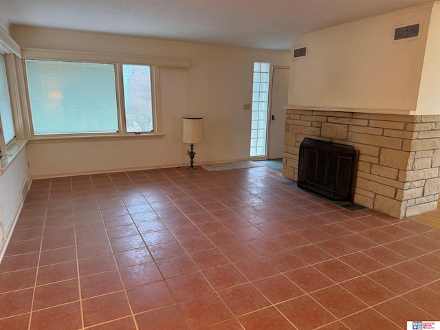 unfurnished living room with a stone fireplace and dark tile patterned floors