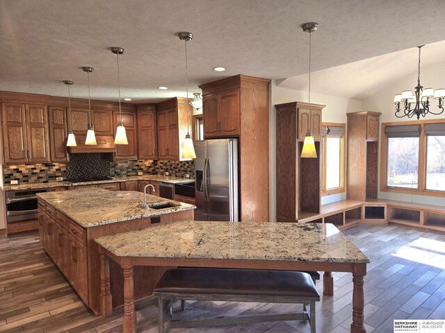 kitchen with stainless steel appliances, a notable chandelier, a spacious island, pendant lighting, and lofted ceiling