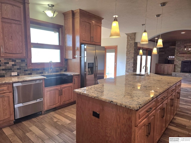 kitchen featuring sink, a center island, stainless steel appliances, pendant lighting, and decorative backsplash