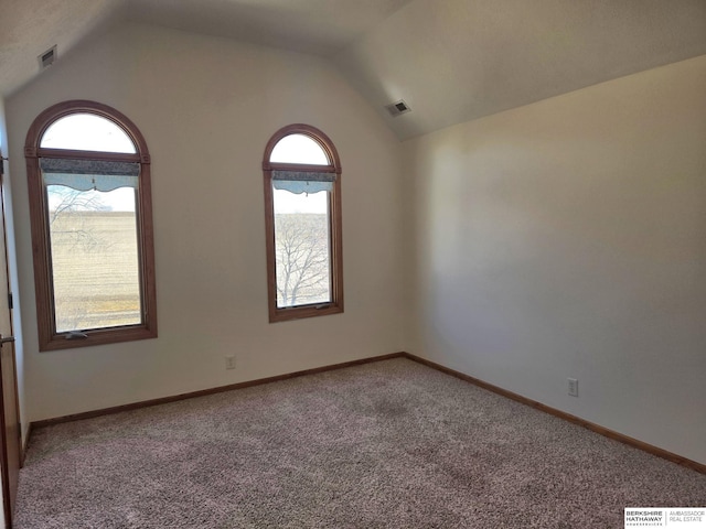 carpeted spare room with lofted ceiling