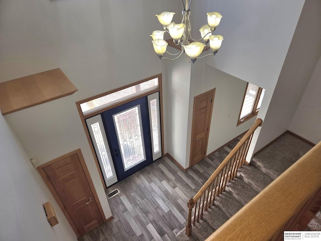 entryway with a high ceiling, an inviting chandelier, a wealth of natural light, and dark wood-type flooring