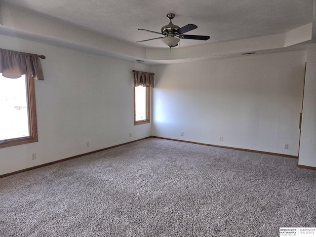 carpeted spare room featuring ceiling fan and a tray ceiling