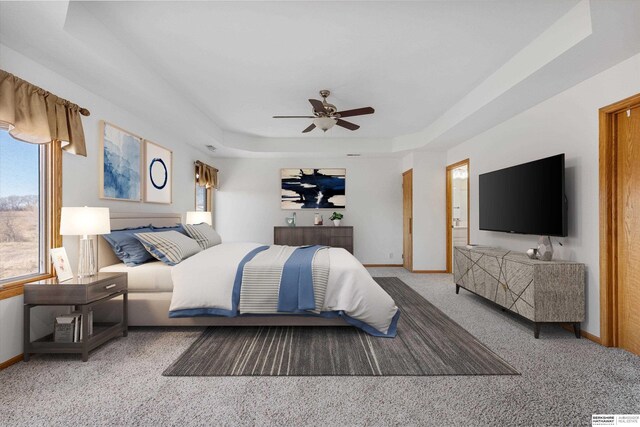 bedroom with ceiling fan, a raised ceiling, carpet floors, and connected bathroom