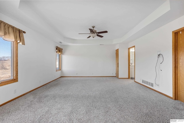 unfurnished room with ceiling fan, a raised ceiling, and carpet floors