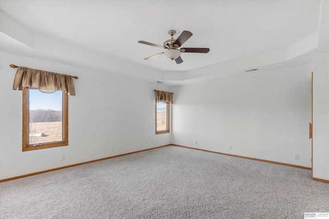 empty room featuring carpet, ceiling fan, and a raised ceiling