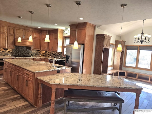 kitchen with stainless steel refrigerator with ice dispenser, vaulted ceiling, pendant lighting, and a large island