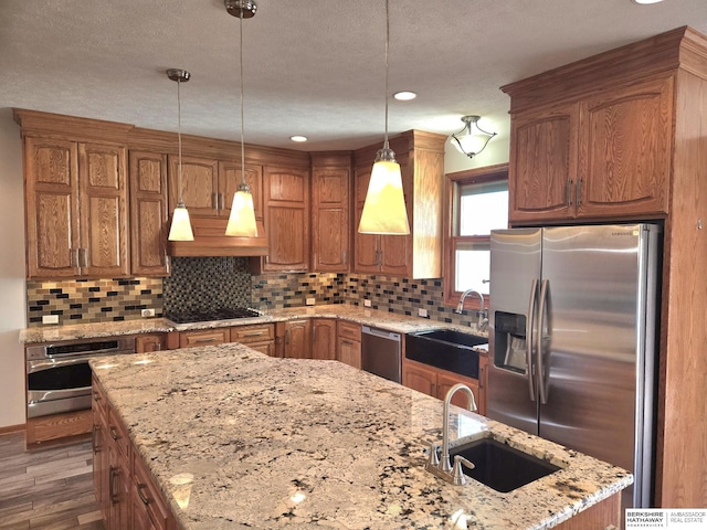 kitchen with custom exhaust hood, stainless steel appliances, sink, a center island, and hanging light fixtures