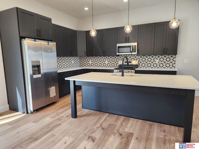 kitchen with appliances with stainless steel finishes, light hardwood / wood-style floors, pendant lighting, and sink