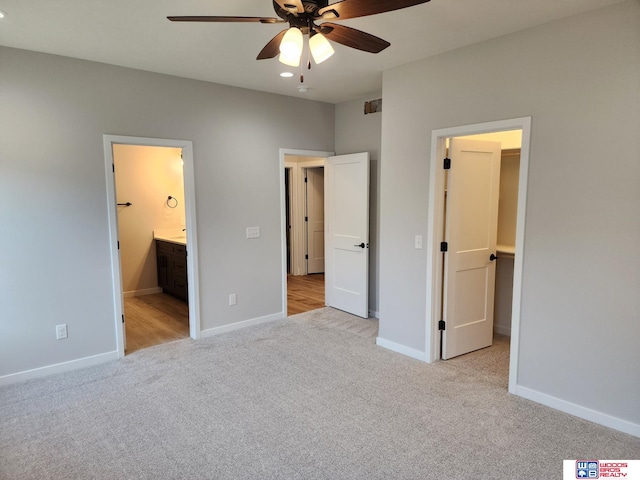 unfurnished bedroom with ensuite bathroom, ceiling fan, and light colored carpet