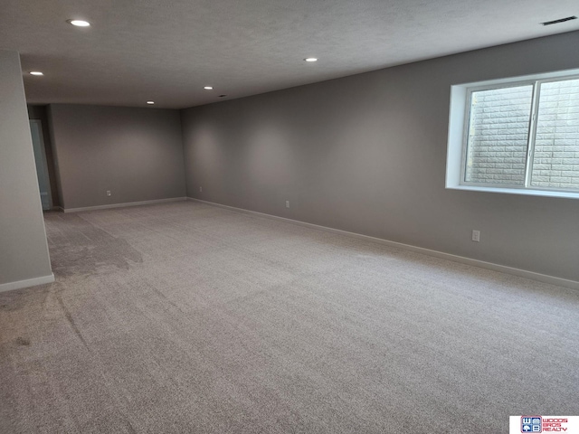 spare room with a textured ceiling and light colored carpet