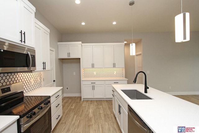 kitchen featuring backsplash, stainless steel appliances, sink, decorative light fixtures, and white cabinetry