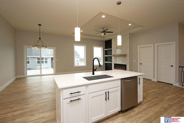 kitchen featuring pendant lighting, a center island with sink, sink, stainless steel dishwasher, and white cabinetry