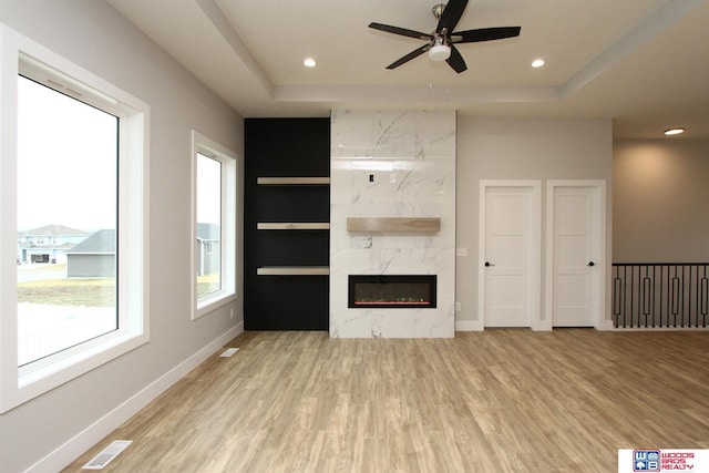 unfurnished living room featuring light hardwood / wood-style flooring, ceiling fan, and a premium fireplace