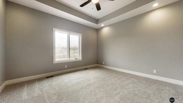 empty room with carpet, a raised ceiling, and ceiling fan