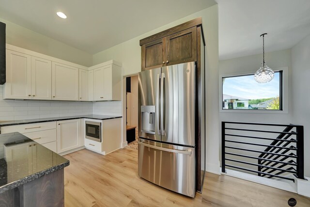 kitchen featuring stainless steel fridge, built in microwave, tasteful backsplash, decorative light fixtures, and white cabinetry