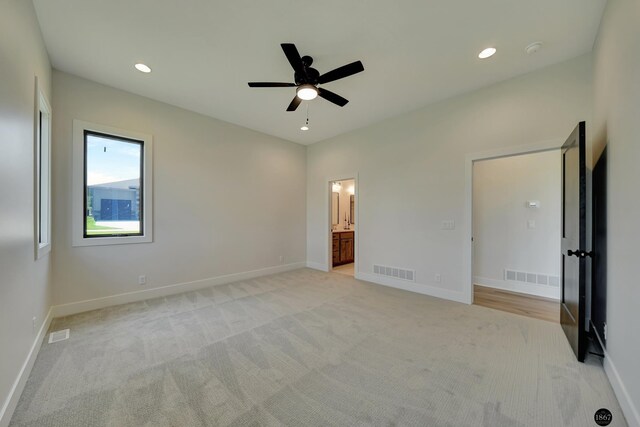 unfurnished bedroom featuring connected bathroom, light colored carpet, and ceiling fan