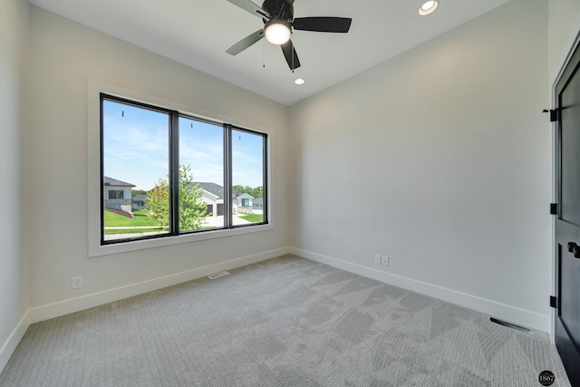 unfurnished room with a wealth of natural light, ceiling fan, and light colored carpet