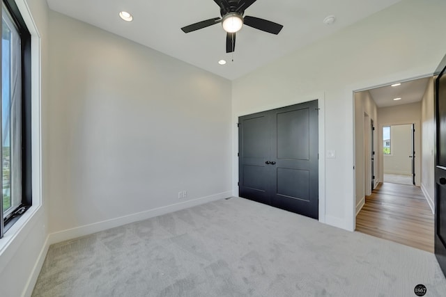 unfurnished bedroom with light carpet, a closet, and ceiling fan