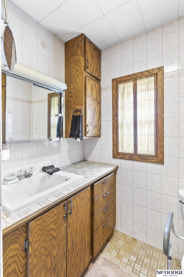 kitchen with light tile patterned flooring, tile walls, and sink