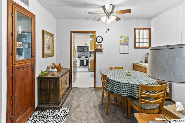 dining area featuring ceiling fan, light colored carpet, and ornamental molding