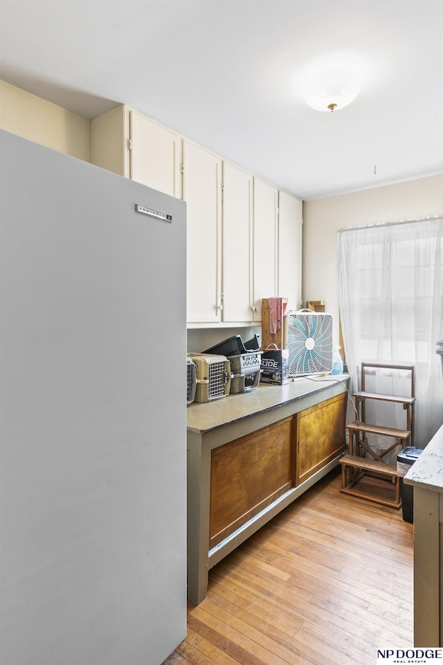 kitchen with white cabinetry, light hardwood / wood-style flooring, and refrigerator