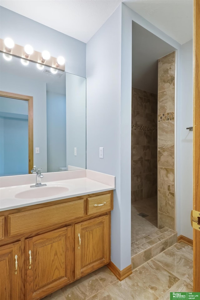 bathroom featuring a tile shower and vanity