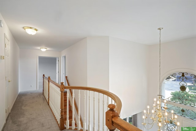 hall featuring light colored carpet and an inviting chandelier