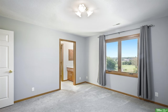 unfurnished bedroom featuring ensuite bathroom and light colored carpet