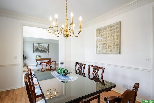 dining area featuring hardwood / wood-style flooring, ornamental molding, and a chandelier