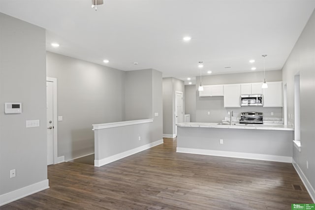 kitchen featuring dark hardwood / wood-style floors, kitchen peninsula, pendant lighting, white cabinets, and appliances with stainless steel finishes